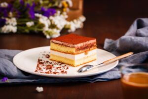 Part de tiramisu dans une assiette blanche avec une cuillère à dessert
