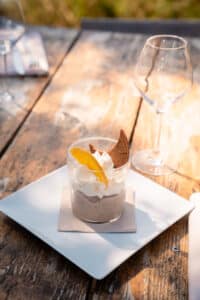 Dessert au chocolat et crème fouettée dans un verre, garni d'une tranche d'orange, sur une table en bois rustique.