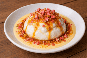 Luxueuse île flottante: dôme de meringue sur crème anglaise, nappé de caramel et saupoudré de morceaux de pralines roses.