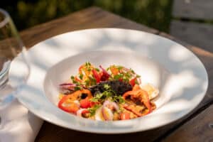 Salade gourmande aux poivrons rouges, œufs et tapenade noire servie en terrasse ensoleillée.