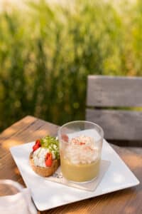 Verrine de velouté avec mousse et bruschetta aux tomates sur une terrasse ensoleillée. Serviette 100% Recycled.