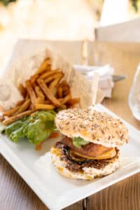 Burger végétarien aux graines, galette panée, aubergine, frites et salade sur assiette.
