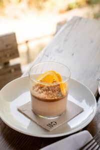 Mousse chocolat, crumble et orange en verre sur assiette. Serviette 100% Recycled. Dessert gourmand en terrasse.