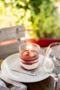 Panna cotta aux fraises en couches dans un verre, table en terrasse, serviette 100% Recycled.