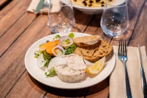 Rillettes de poisson, pain grillé et salade fraîche servis sur une table en bois dans un restaurant.