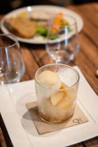 Sorbet à la poire et fruits pochés servis dans un verre sur une serviette en papier FSC et assiette blanche.